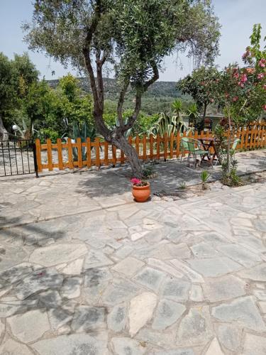 un albero in un patio in pietra con recinzione di Giola aparments and studios 2 ad Astrís