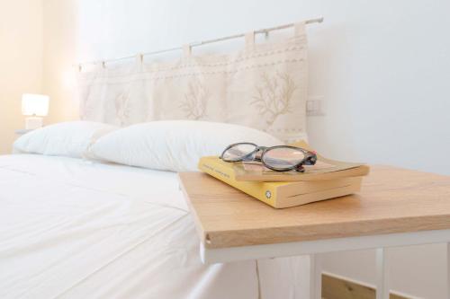 a pair of glasses sitting on a table next to a bed at Domo Green House in Villasimius