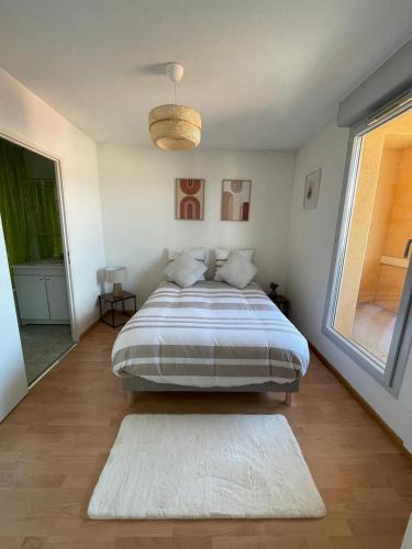 une chambre avec un grand lit et une grande fenêtre dans l'établissement City Rose T2, Climatisation,parking privé, piscine, wifi , tout confort, à Toulouse