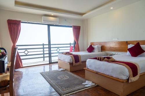 a hotel room with two beds and a large window at Nagarkot Shangrila Resort in Nagarkot