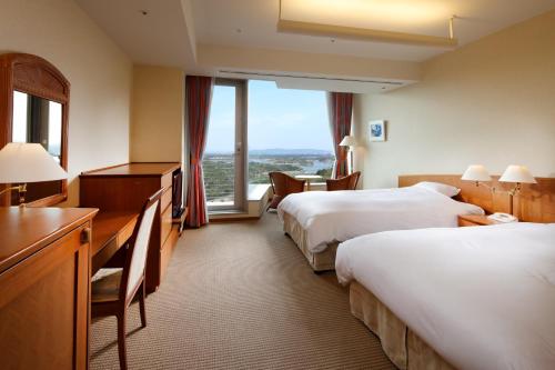 a hotel room with two beds and a desk at Miyako Resort Okushima Aqua Forest (Hotel Kintetsu Aqua Villa Ise Shima) in Shima