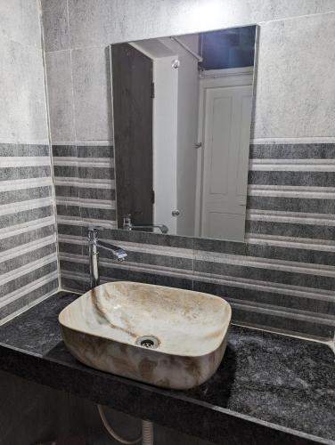 a sink in a bathroom with a large mirror at The Aruj Home Stay in Kolhapur