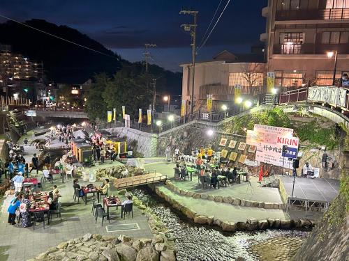 神戶的住宿－KAMENOI HOTEL Arima，一群人晚上坐在河边的桌子旁