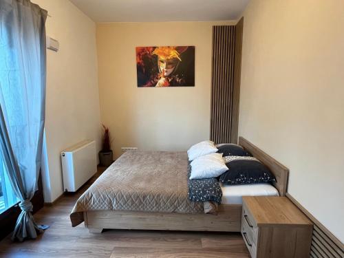 a bedroom with a bed and a painting on the wall at Apartament Serce Miasta in Wrocław