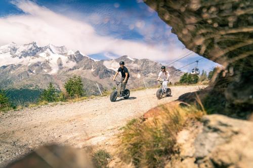 two people riding bikes on a dirt road with mountains in the background at Sunshine in Saas-Grund