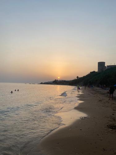 a group of people walking on the beach at sunset at TorrediGaffe Home, una casa nella piazzetta del borgo a due passi dal mare in Torre di Gaffe