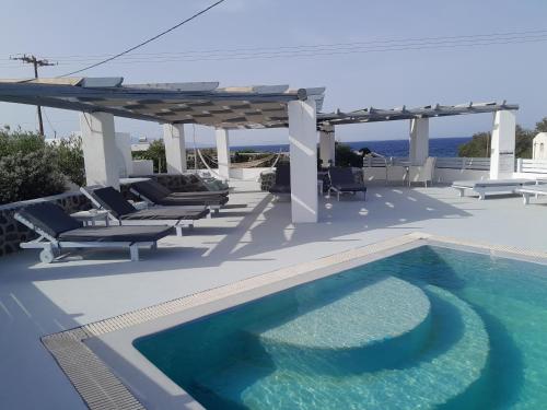 a swimming pool with chairs and a pergola on a patio at Atlantis - by S paradise - outdoor jacuzzi & seaview in Oia
