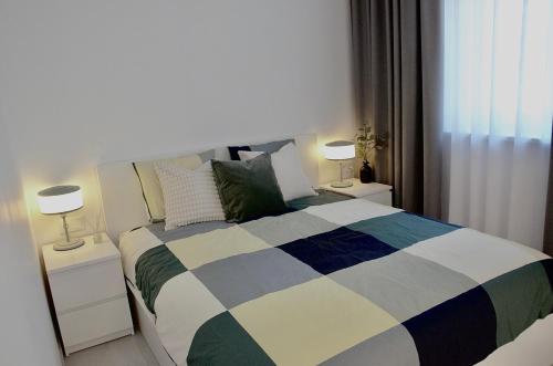 a bedroom with a bed with two night stands and two lamps at Mazvydo studio appartment in Klaipėda