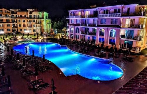 a large swimming pool in front of buildings at night at Golden Hacienda in Sozopol