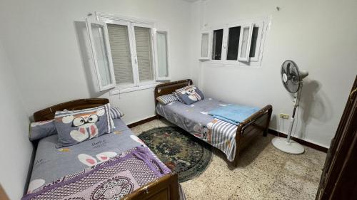 1 dormitorio con 2 camas individuales y ventilador en شقق وشاليهات بمدينة النورس, en Ismailía