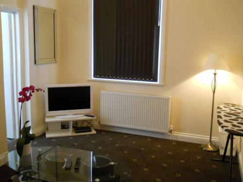 a living room with a television and a window at Citystay Hotel in London