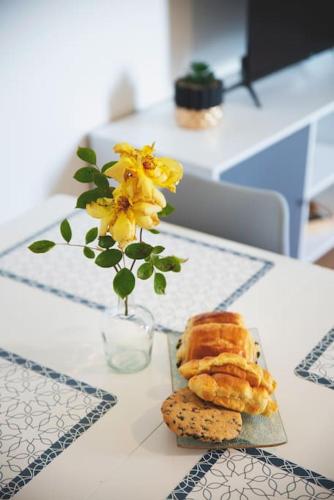 une table avec un vase avec des fleurs jaunes et des biscuits dans l'établissement Le St Gemmes : Appartement T3, à Sainte-Gemme-sur-Loire