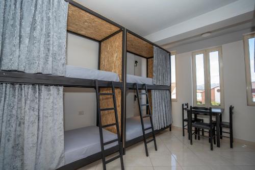 Zimmer mit 3 Etagenbetten und einem Tisch in der Unterkunft Golden Sleep Hostel in Shkodra