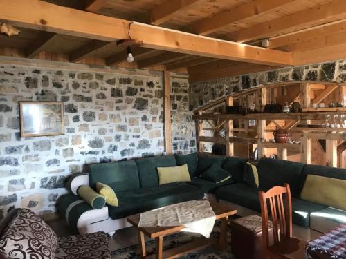 a living room with a green couch and a stone wall at Shpia e Las Vol in Vasije