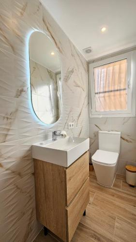 a bathroom with a sink and a mirror and a toilet at Boho Arenal Bol in Calpe