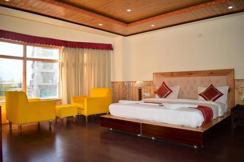 een slaapkamer met een bed en enkele gele stoelen bij zoz f3 in Leh