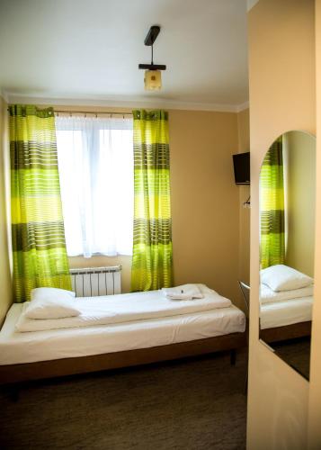 a small room with a bed with a window at Zajazd Wrota Lasu in Hajnówka