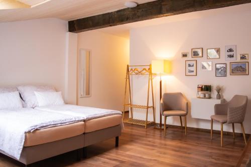 a bedroom with a bed and two chairs at Ubytovanie CA - comfy apartments in Čadca