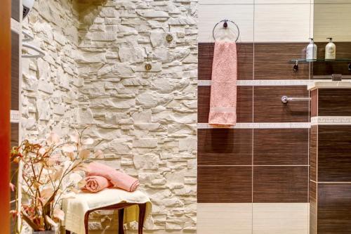 a bathroom with a stone wall and a pink towel at APARTAMENT & SPA Dworski Zakątek in Reda