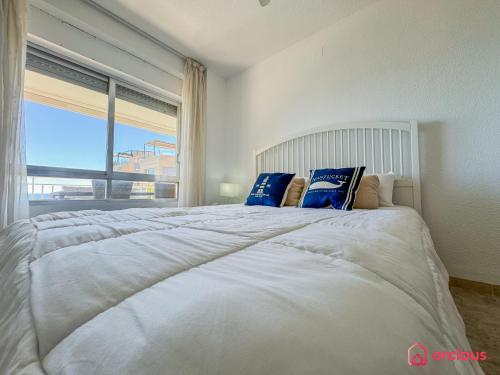 une chambre avec un grand lit blanc avec une grande fenêtre dans l'établissement La Postal, à Benicàssim