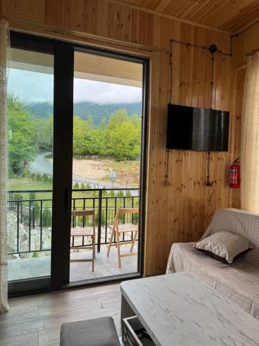 a room with a bed and a large window at Cottage ,,Okatsia” ოკაციას კოტეჯები in Gordi