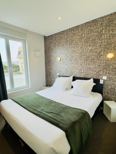 a bedroom with a large bed and a window at Le Clos Normand in Saint-Aubin-sur-Mer