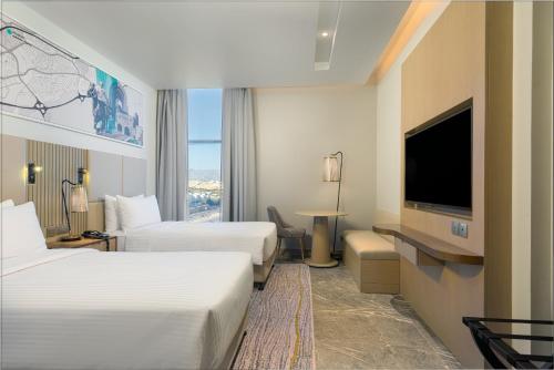 Habitación de hotel con 2 camas y TV de pantalla plana. en IntercityHotel Bawshar Muscat en Mascate