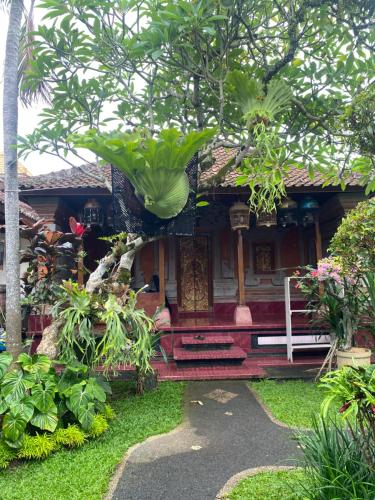 a house in a garden with trees and plants at Suryadina Guest House in Ubud