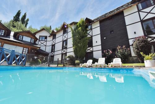 a swimming pool with two chairs and a building at Plaza Mayor by Visionnaire in San Martín de los Andes