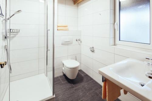 a white bathroom with a toilet and a sink at KAISERS das kleine Stadthotel in Sonthofen