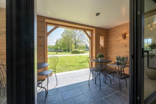a room with a patio with chairs and tables at Hoeve den Akker - luxueuze vakantiewoningen met privétuinen en alpaca's nabij Brugge, Damme, Knokke, Sluis en Cadzand in Damme