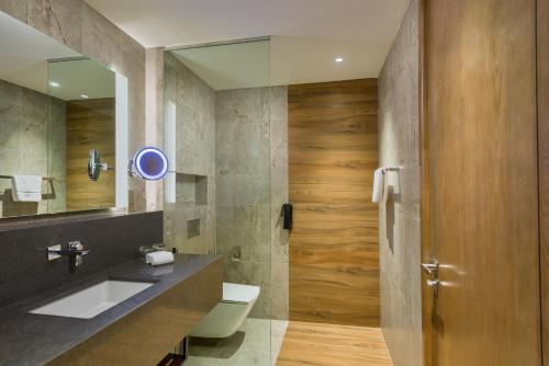 a bathroom with a sink and a toilet and a mirror at IntercityHotel Bawshar Muscat in Muscat