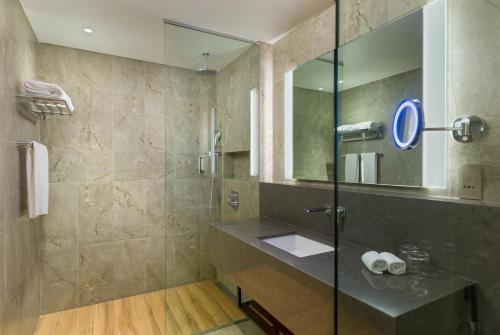 a bathroom with a sink and a shower with a mirror at IntercityHotel Bawshar Muscat in Muscat