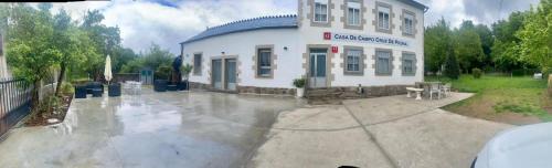 a large white building in the rain in a yard at Casa de Campo Cruz de Pedra in Portomarin