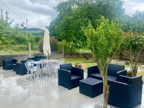 a patio with a table and chairs and an umbrella at Casa de Campo Cruz de Pedra in Portomarin