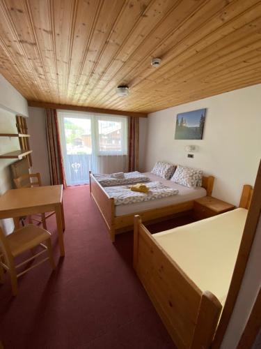 a bedroom with a bed and a table and a chair at Pension Leitenhof in Niederau