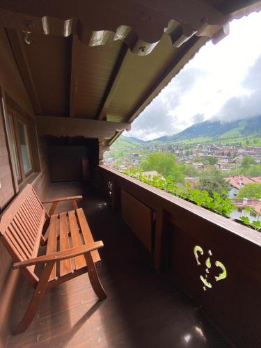 a wooden bench sitting on a balcony with a view at Pension Leitenhof in Niederau