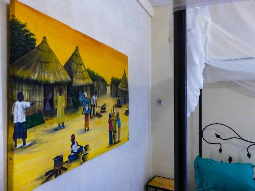 a painting hanging on a wall in a bedroom at Chez Sofia AFRO CHITI in Saint-Louis