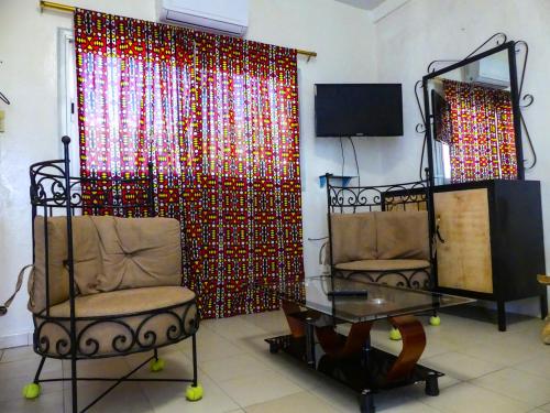 a living room with two chairs and a curtain at Chez Sofia AFRO CHITI in Saint-Louis