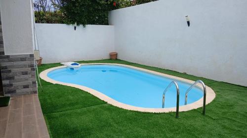a large swimming pool in a yard with grass at Villa avec piscine privée près de Casablanca Maroc in Dar Bouazza