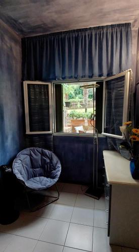 a blue room with a chair and a window at Confortevole Bilocale Giardino Doppio Parcheggio in Punta Ala