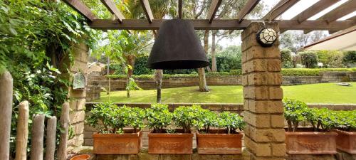 a bell hanging in a garden with potted plants at Confortevole Bilocale Giardino Doppio Parcheggio in Punta Ala