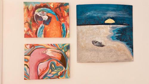 three paintings are hanging on a wall at Confortevole Bilocale Giardino Doppio Parcheggio in Punta Ala