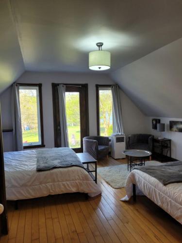 a bedroom with two beds and a living room at Le petit Manoir Spa et Vue sur rivière St Maurice in Grandes-Piles
