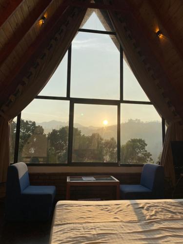 a room with a large window with a bed and two chairs at Ella nine arch spice garden in Ella