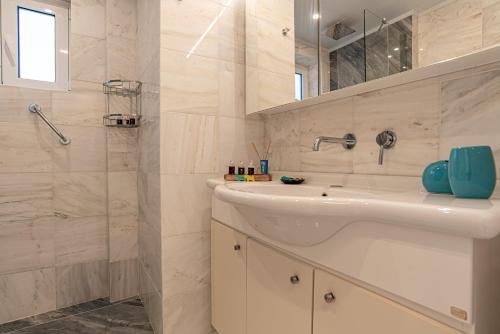 a white bathroom with a sink and a shower at Feliz Apt- Breathtaking Seaview and Sunset by ΜΡS in Anavyssos