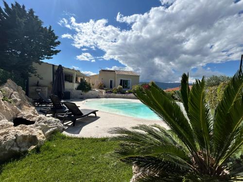 une piscine avec deux chaises et une maison dans l'établissement Duplex Oliveraie piscine au sel marin et parking, à Nice