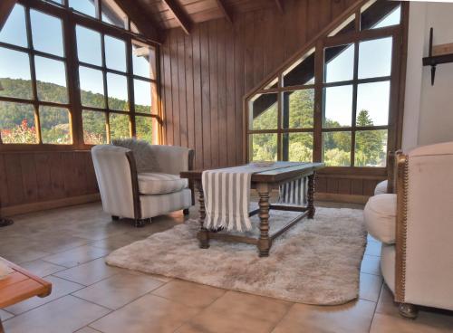 a living room with a table and chairs and windows at Hotel Caupolican by Visionnaire in San Martín de los Andes