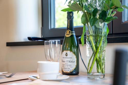 a bottle of champagne next to a glass and a vase at Hoeve den Akker - luxueuze vakantiewoningen met privétuinen en alpaca's nabij Brugge, Damme, Knokke, Sluis en Cadzand in Damme