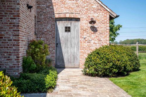 a wooden door on the side of a brick building at Hoeve den Akker - luxueuze vakantiewoningen met privétuinen en alpaca's nabij Brugge, Damme, Knokke, Sluis en Cadzand in Damme